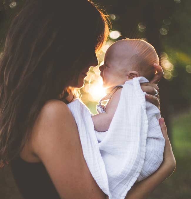 mom holding baby natural setting outside