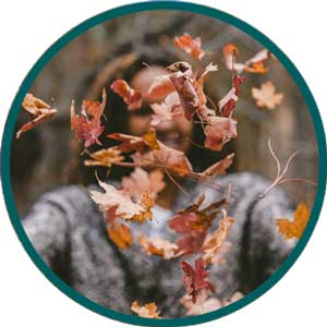 woman throwing autumn leaves